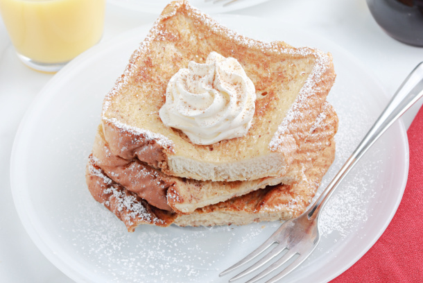 Easy Eggnog French Toast - a white plate with Eggnog French Toast, topped with whipped cream and powdered sugar - Kids Activities Blog 