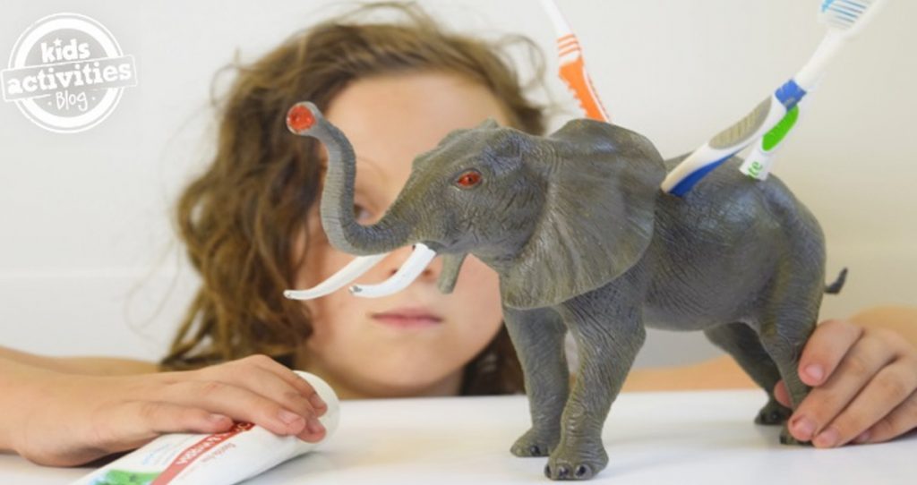 ideas for christmas homemade gifts- Girl holding elephant toy modified to look like a toothbrush holder with toothbrushes in it.