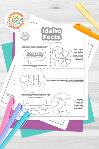 Black and white coloring pages with Idaho facts lying on top of blue-green and purple sheets with assorted crayons on a dark grey background.