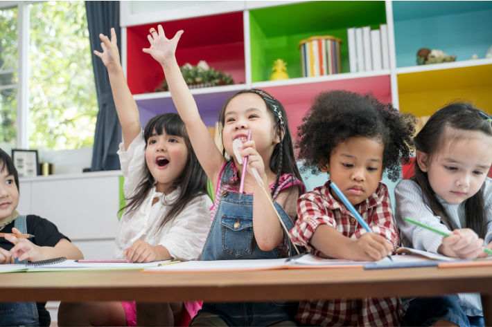 Kindergarten activities for Kindergarten classroom - Kids Activities Blog - kindergarten students raising hands while working at desk