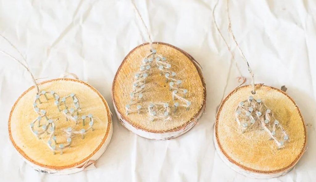 natural Christmas ornaments- Image shows three rustic twine wood slice ornaments on a table.