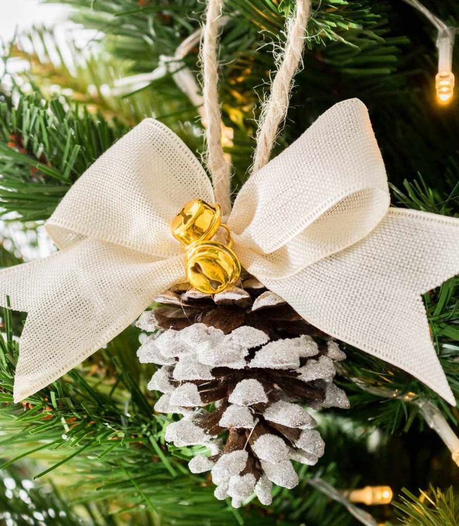 natural Christmas ornaments- Image shows a rustic flocked pinecone christmas ornament hanging from a tree.