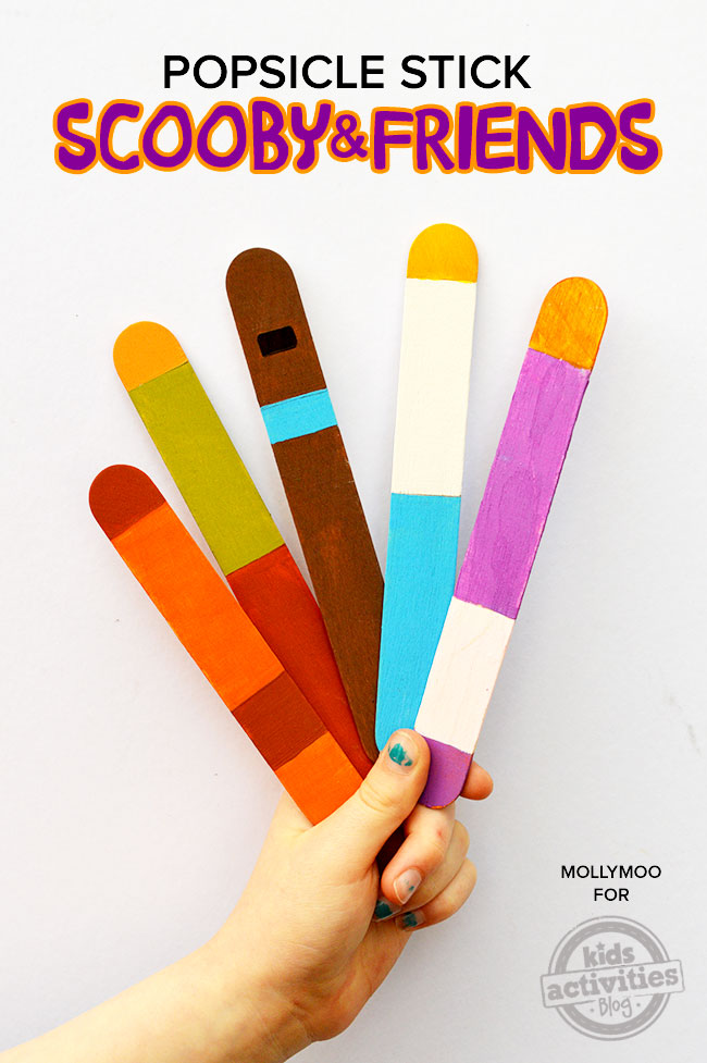 text: Popsicle stick Scooby and Friends - finished scooby doo popsicle stick crafts for kids shown held by hand with white background