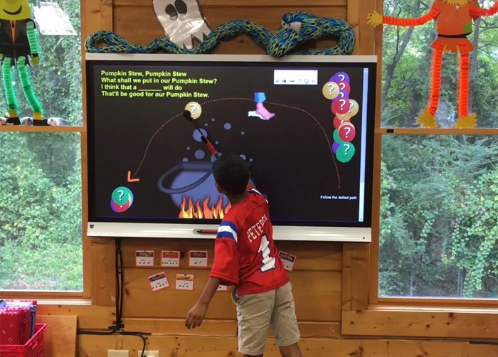 games for smartboard- Image shows a preschoolers playing with a smartboard. From 